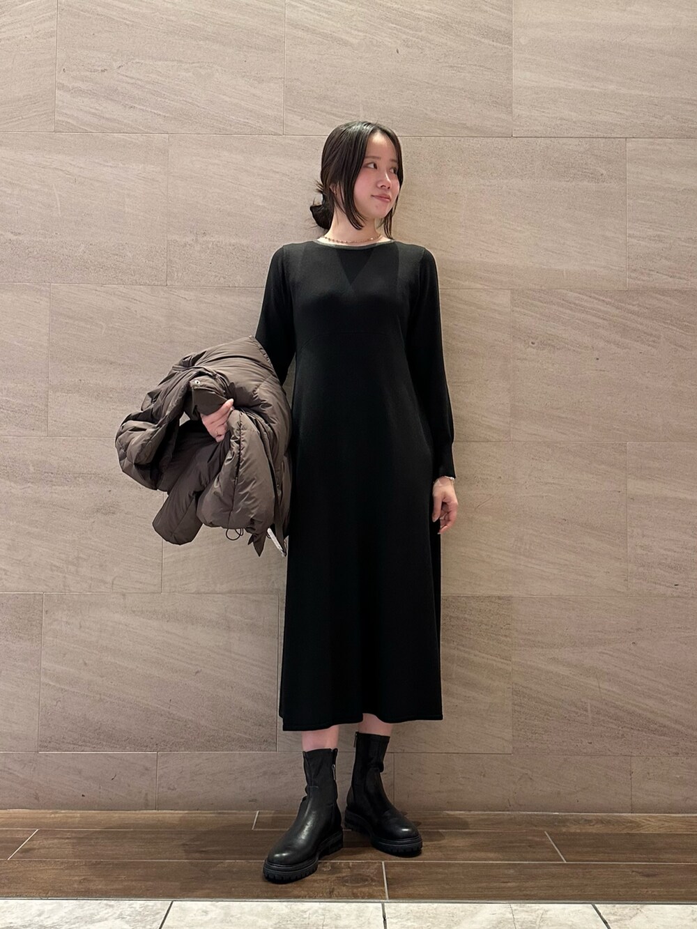 ブラック系のワンピース、ベージュ系のトートバッグ、ブラック系のブーツを着用したレディースの冬コーディネートの2枚目の写真
