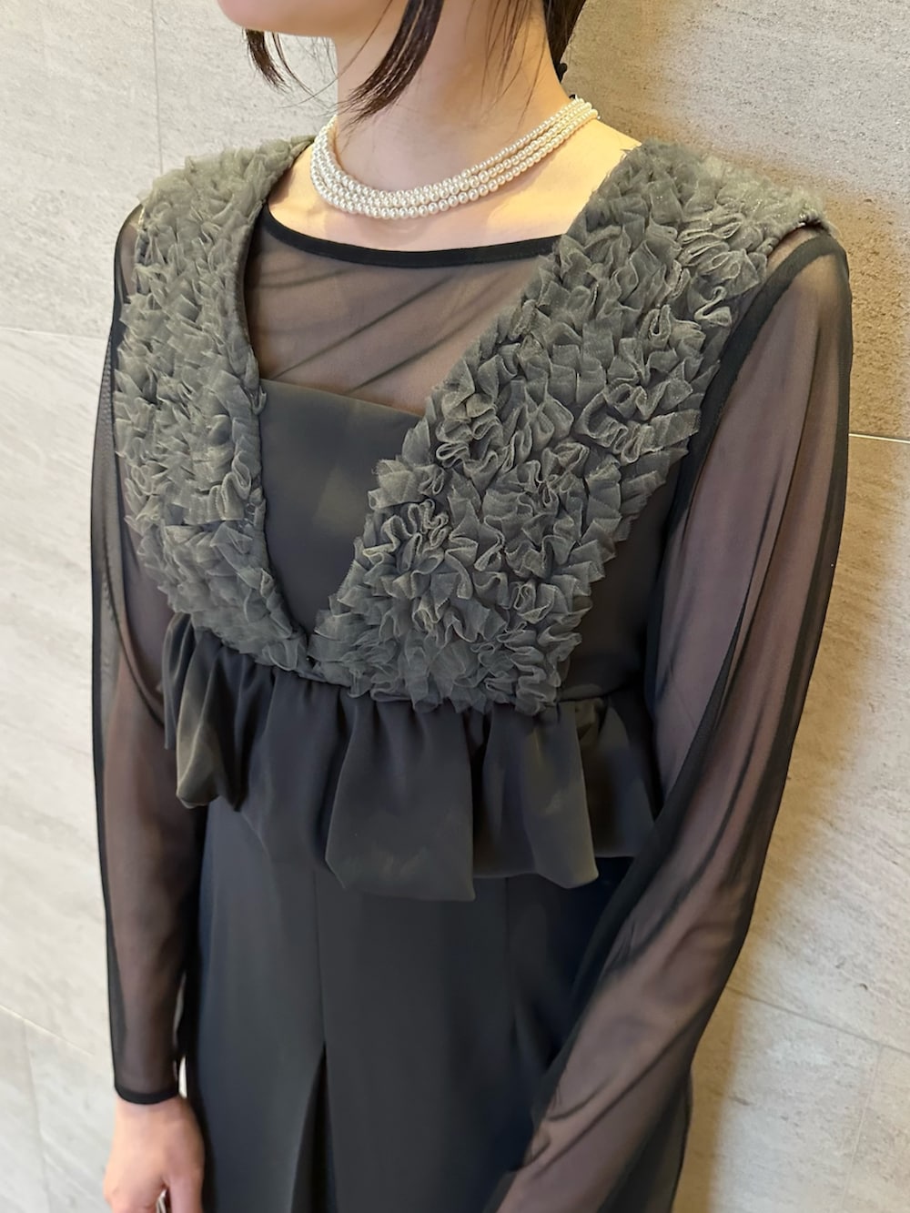 グレー系のワンピース、シルバー系のハンドバッグ、ホワイト系のネックレスを着用したレディースの春コーディネートの5枚目の写真