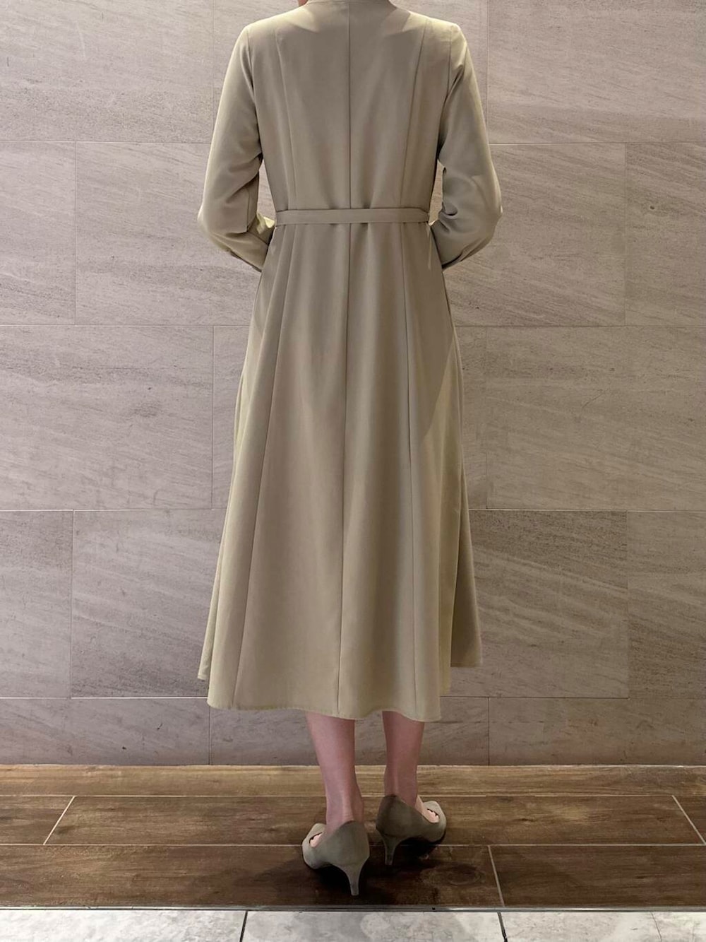 ブラウン系のパンプス、ブラック系のハンドバッグ、ベージュ系のワンピースを着用したレディースの冬コーディネートの5枚目の写真