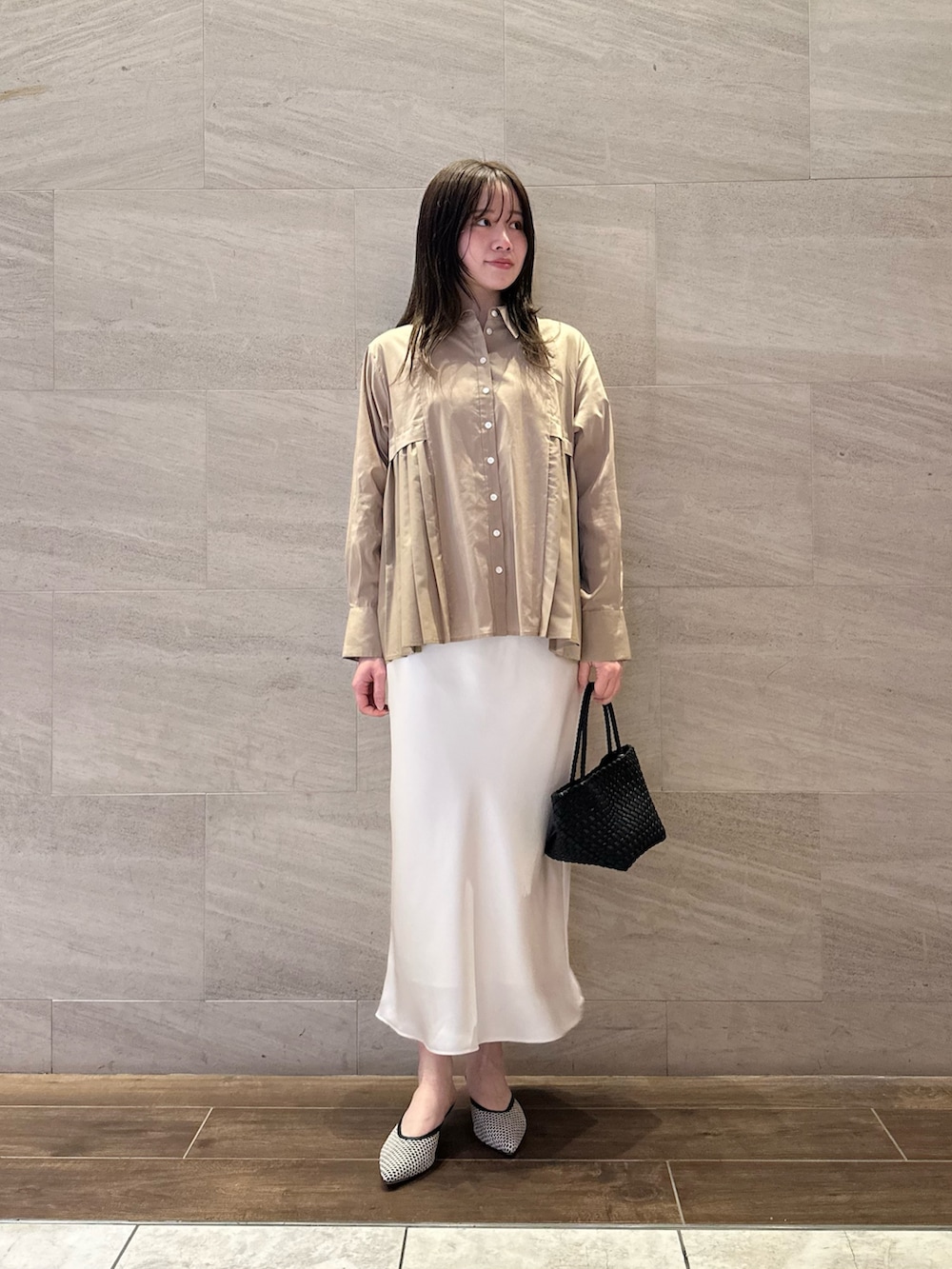 ベージュ系のシャツ/ブラウス、ホワイト系のスカート、ブラック系のトートバッグを着用したレディースの春コーディネートの2枚目の写真