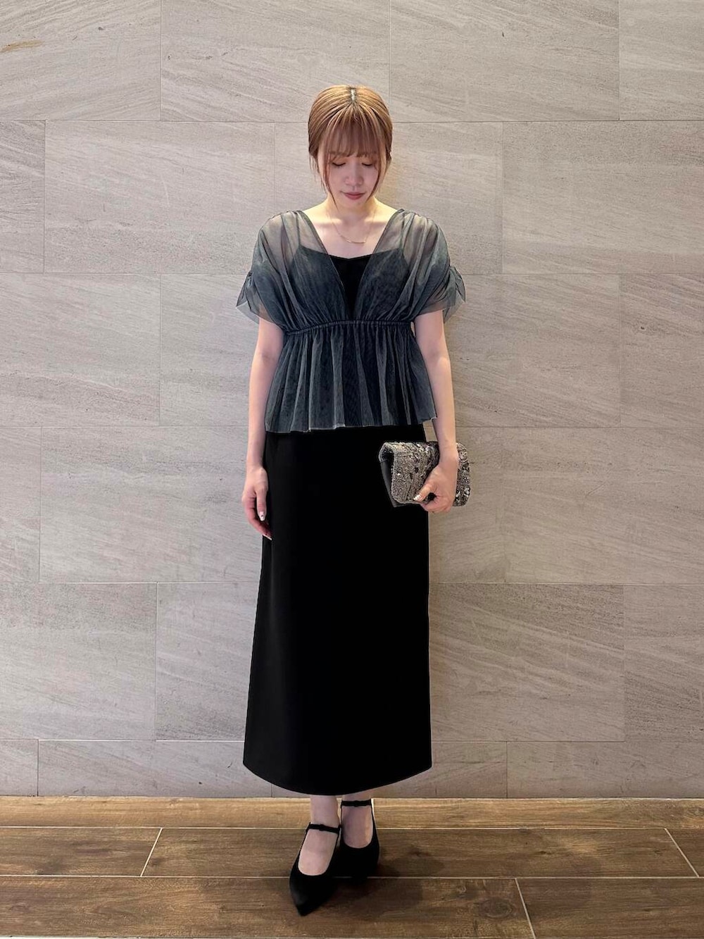 ゴールド系のハンドバッグ、ブラック系のパンプス、ブラック系のワンピースを着用したレディースの夏コーディネートの3枚目の写真