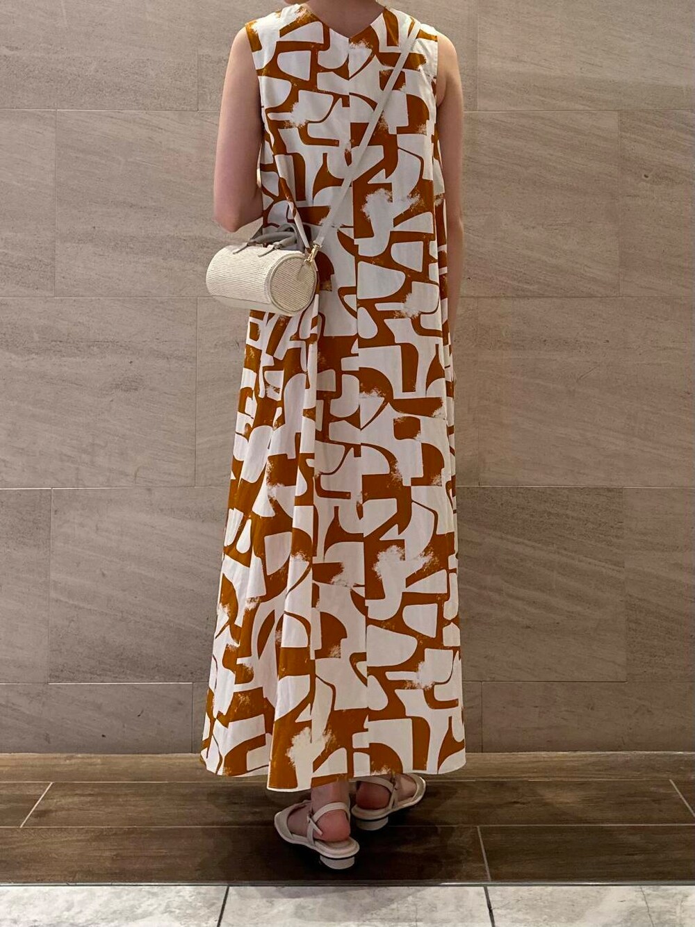 ホワイト系のサンダル、オレンジ系のワンピースを着用したレディースの春コーディネートの5枚目の写真