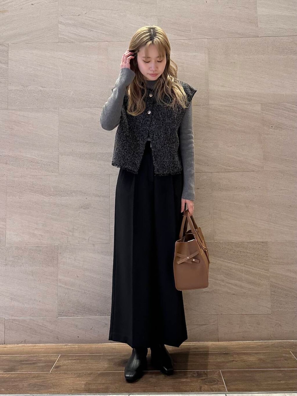 ブラウン系のハンドバッグ、グレー系のニット/セーター、ブラック系のその他パンツを着用したレディースの冬コーディネートの4枚目の写真
