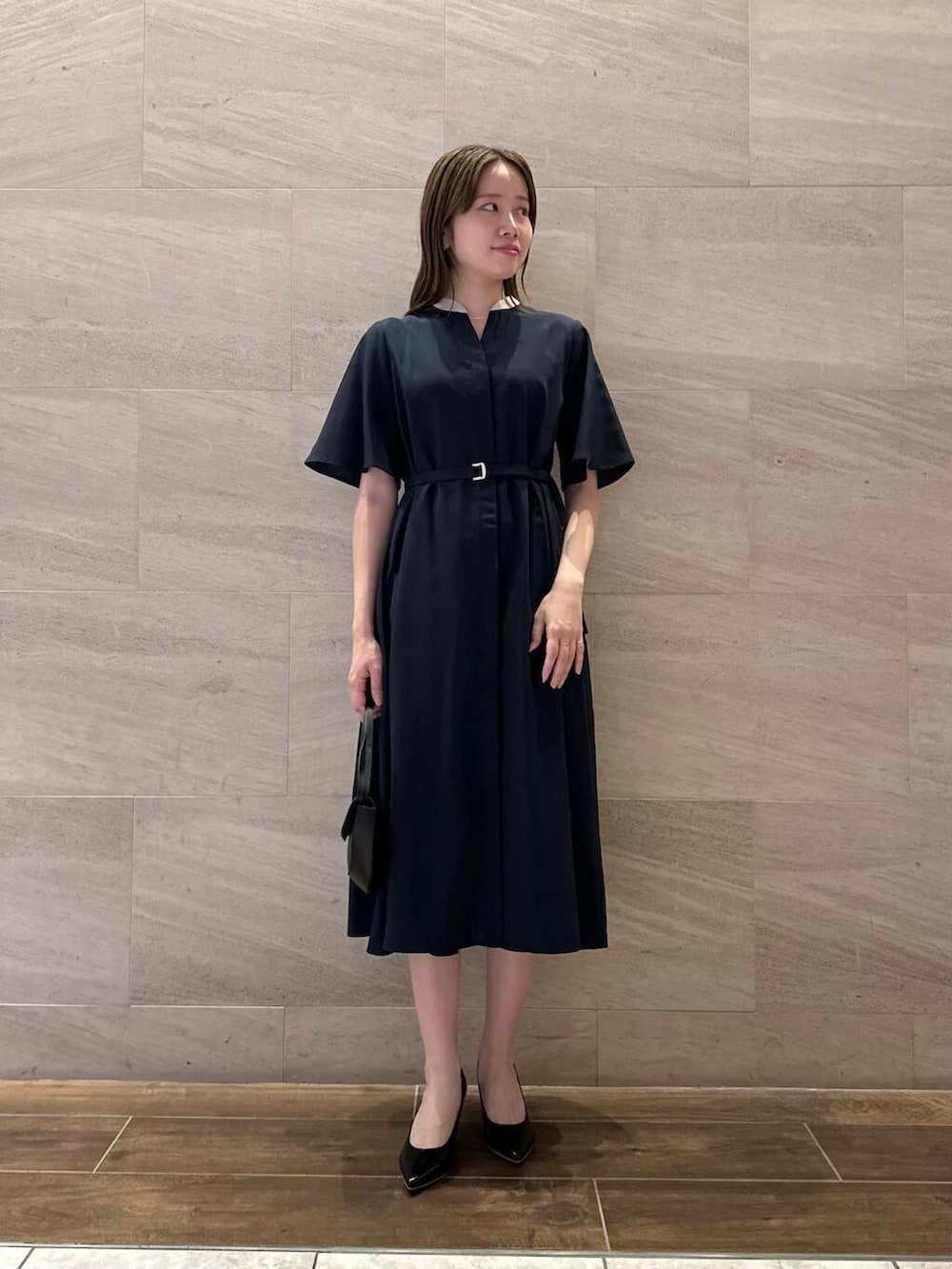 ブラック系のパンプス、ブルー系のワンピース、ブラック系のショルダーバッグを着用したレディースの夏コーディネートの3枚目の写真