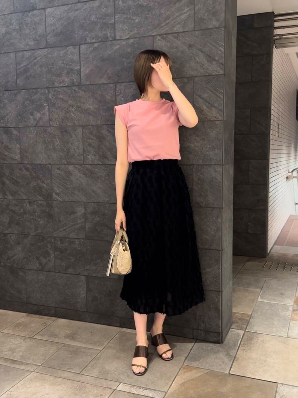 ベージュ系のかごバッグ、ピンク系のTシャツ/カットソー、ブラック系のスカートを着用したレディースの夏コーディネートの3枚目の写真