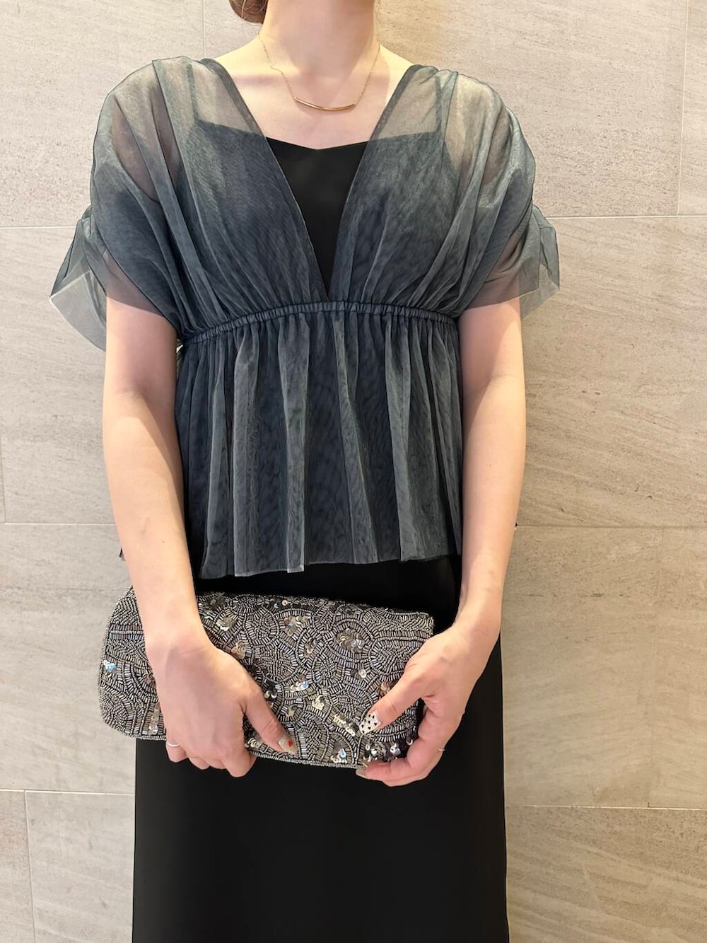 ゴールド系のハンドバッグ、ブラック系のパンプス、ブラック系のワンピースを着用したレディースの夏コーディネートの6枚目の写真