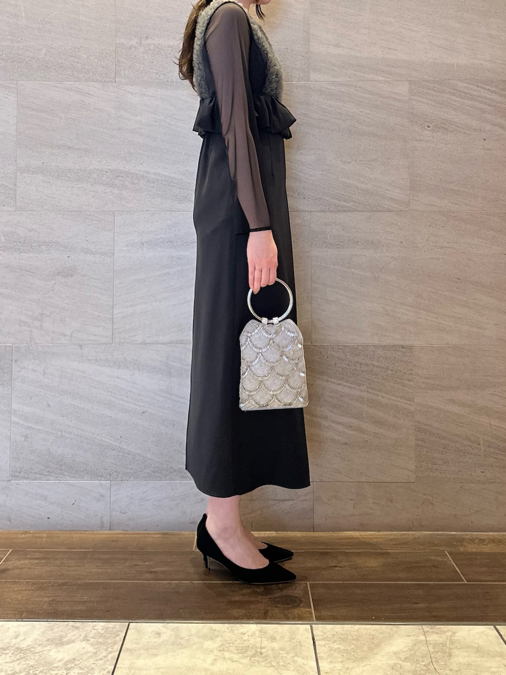 グレー系のワンピース、シルバー系のハンドバッグ、ホワイト系のネックレスを着用したレディースの春コーディネートの2枚目の写真