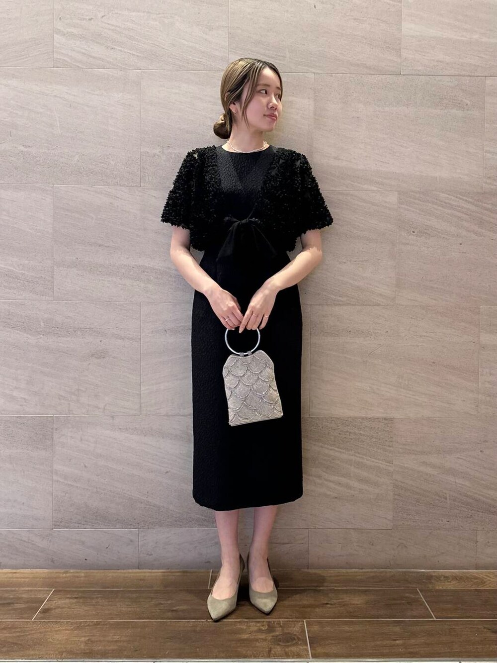 ベージュ系のハンドバッグ、ホワイト系のネックレスを着用したレディースの春コーディネートの3枚目の写真