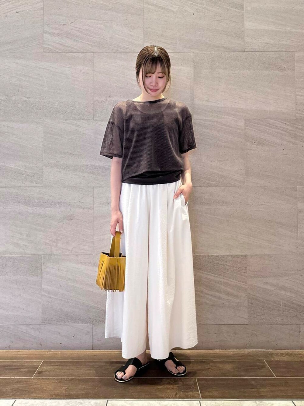 イエロー系のハンドバッグ、ホワイト系のその他パンツ、ブラウン系のTシャツ/カットソーを着用したレディースの夏コーディネートの2枚目の写真