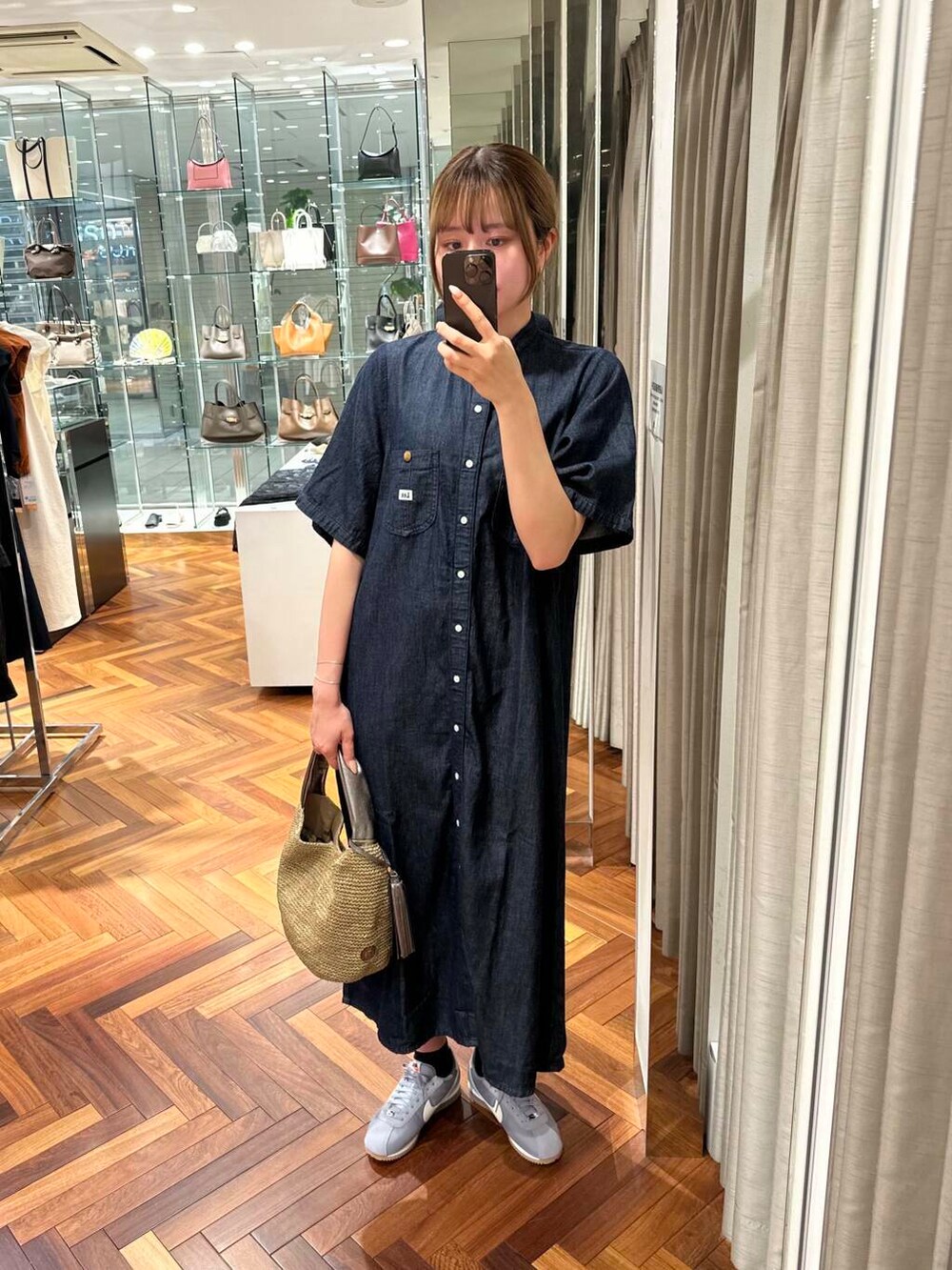 ブラウン系のかごバッグ、ブルー系のワンピース、グレー系のスニーカーを着用したレディースの夏コーディネートの3枚目の写真