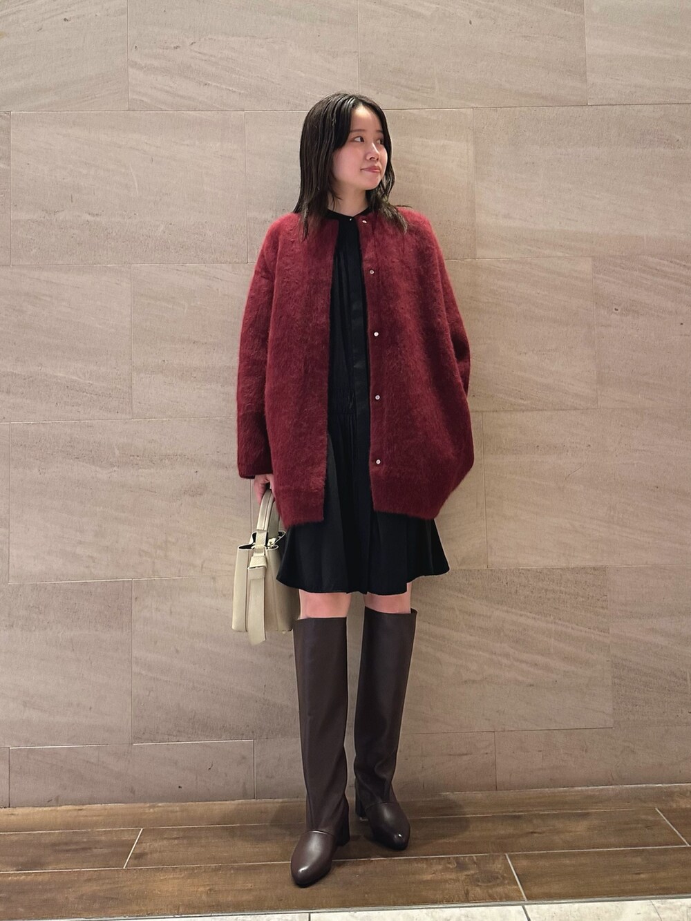 ブラック系のワンピース、レッド系のカーディガン/ボレロ、ベージュ系のハンドバッグを着用したレディースの秋コーディネートの2枚目の写真