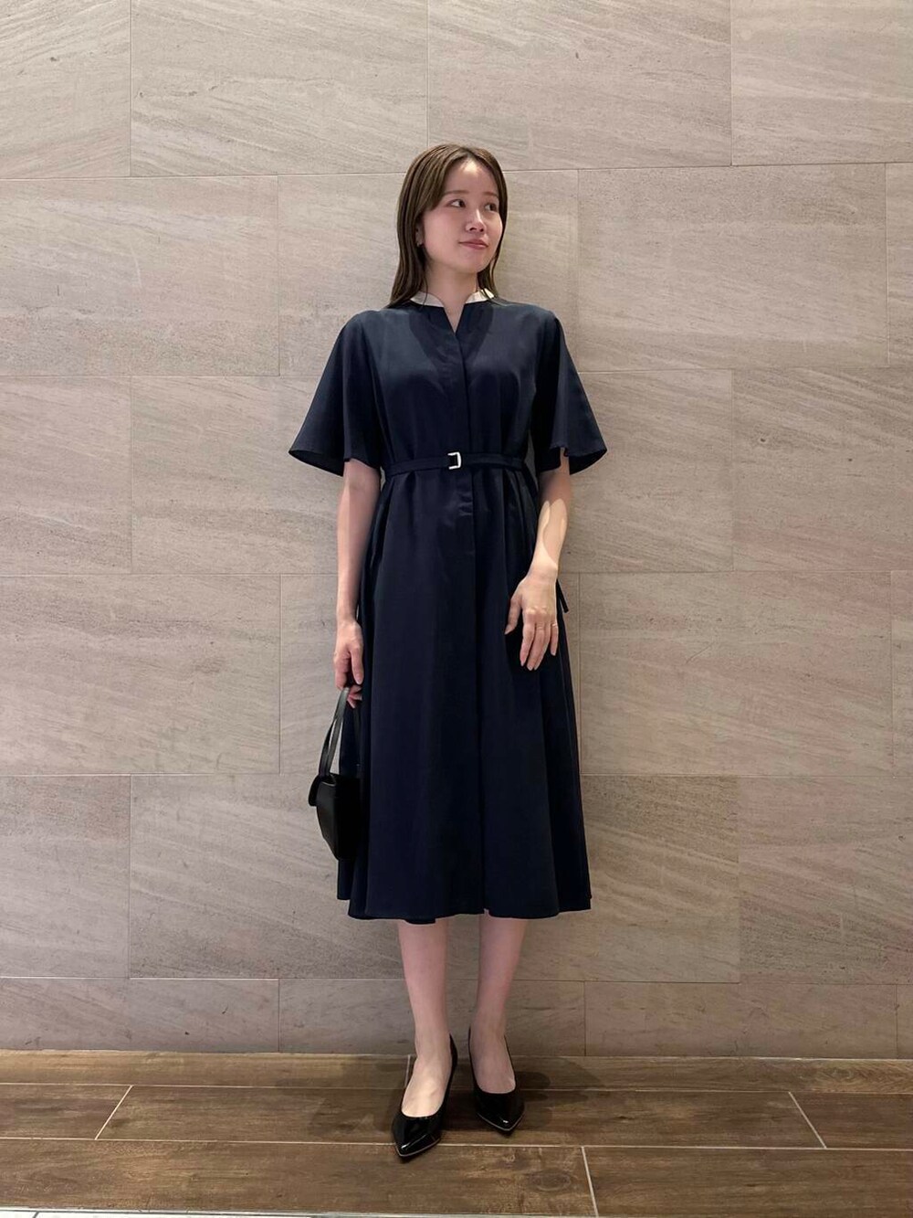 ブラック系のパンプス、ブルー系のワンピース、ブラック系のショルダーバッグを着用したレディースの夏コーディネートの2枚目の写真