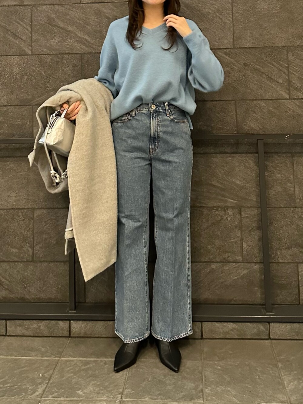 グレー系のその他アウター、ブルー系のニット/セーター、ブルー系のデニムパンツを着用したレディースの冬コーディネートの4枚目の写真
