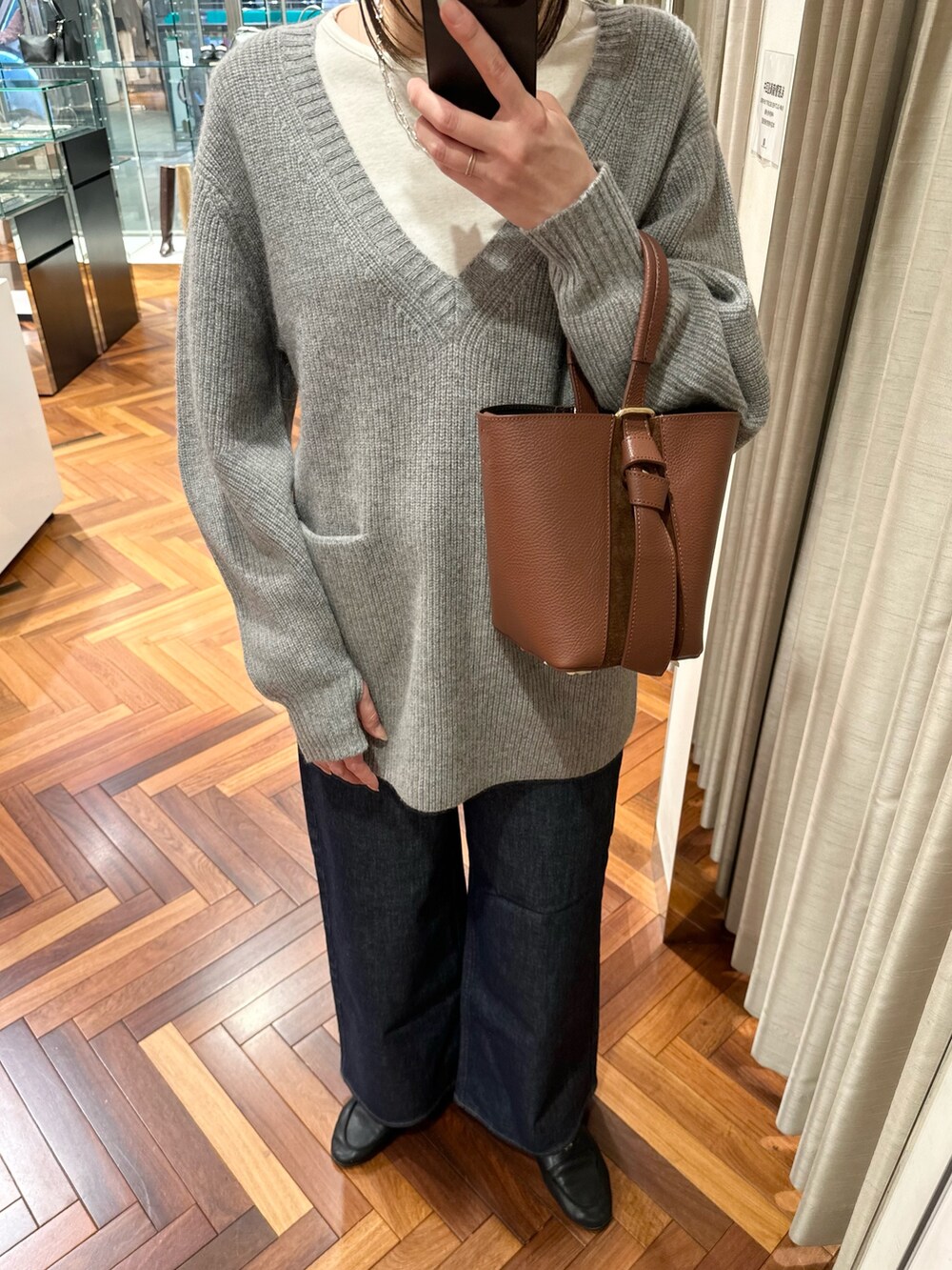 グレー系のニット/セーター、ホワイト系のTシャツ/カットソー、ブルー系のデニムパンツを着用したレディースの秋コーディネートの4枚目の写真