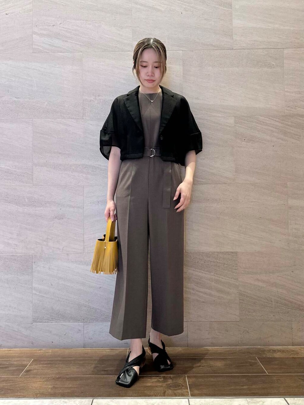 イエロー系のハンドバッグ、ブラック系のその他アウター、ブラウン系のサロペット/オーバーオールを着用したレディースの春コーディネートの2枚目の写真