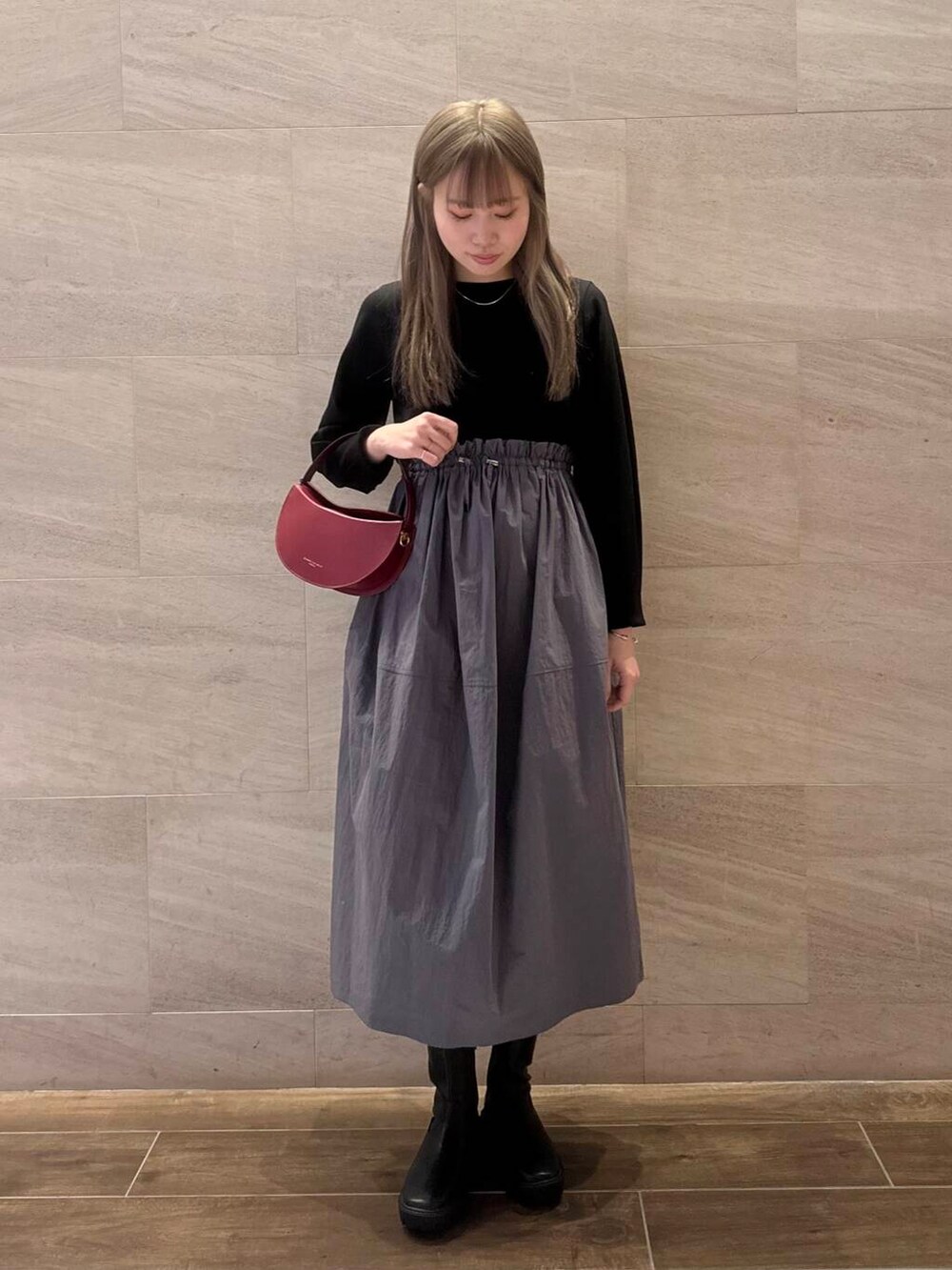 ブラック系のブーツ、ブラック系のワンピース、レッド系のハンドバッグを着用したレディースの冬コーディネートの6枚目の写真