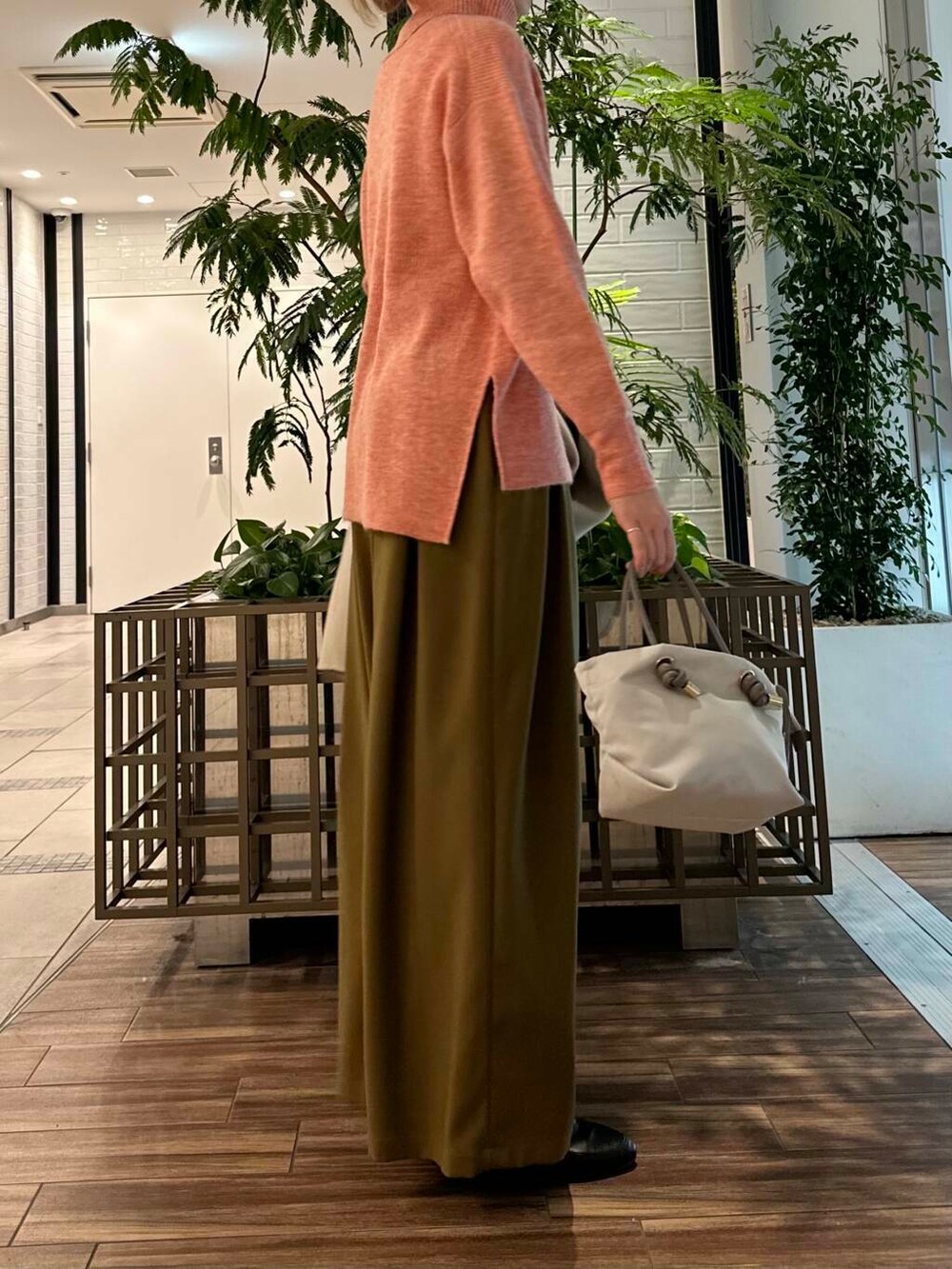 ベージュ系のステンカラーコート、ベージュ系のその他パンツ、ピンク系のニット/セーターを着用したレディースの冬コーディネートの5枚目の写真