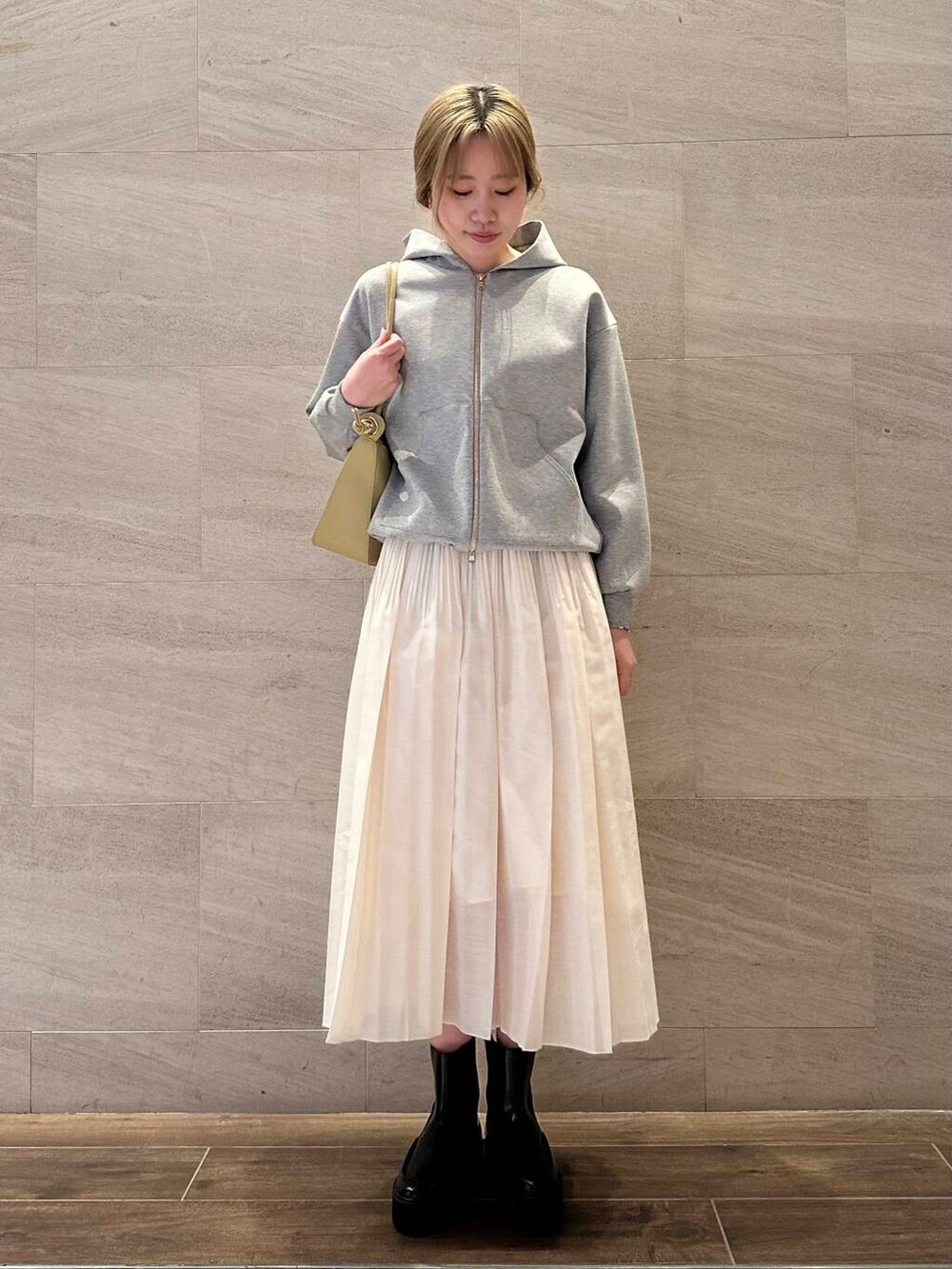 グレー系のブルゾン、ホワイト系のスカート、ベージュ系のショルダーバッグを着用したレディースの冬コーディネートの3枚目の写真