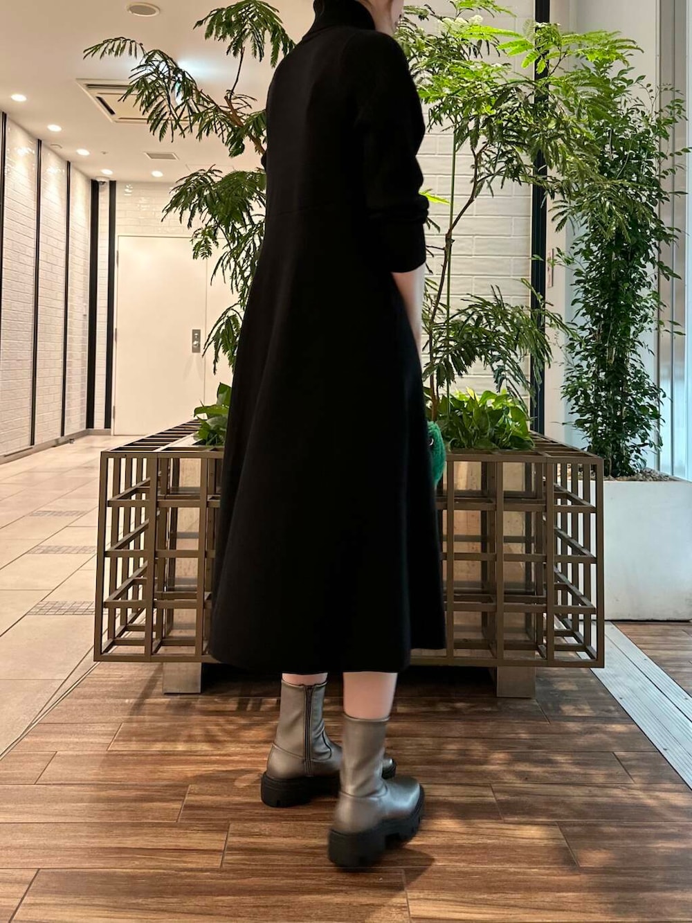 シルバー系のブーツ、ブラック系のワンピース、グリーン系のショルダーバッグを着用したレディースの秋コーディネートの4枚目の写真