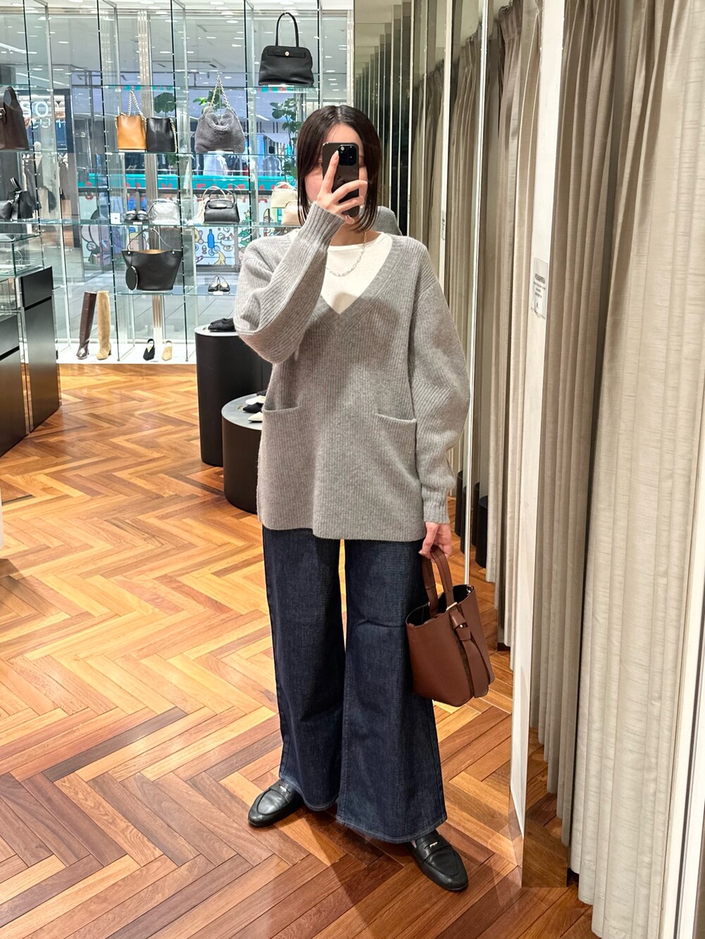 グレー系のニット/セーター、ホワイト系のTシャツ/カットソー、ブルー系のデニムパンツを着用したレディースの秋コーディネートの5枚目の写真