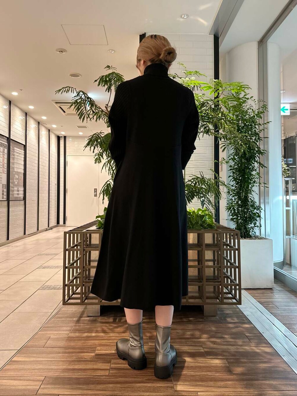 シルバー系のブーツ、ブラック系のワンピース、グリーン系のショルダーバッグを着用したレディースの秋コーディネートの2枚目の写真