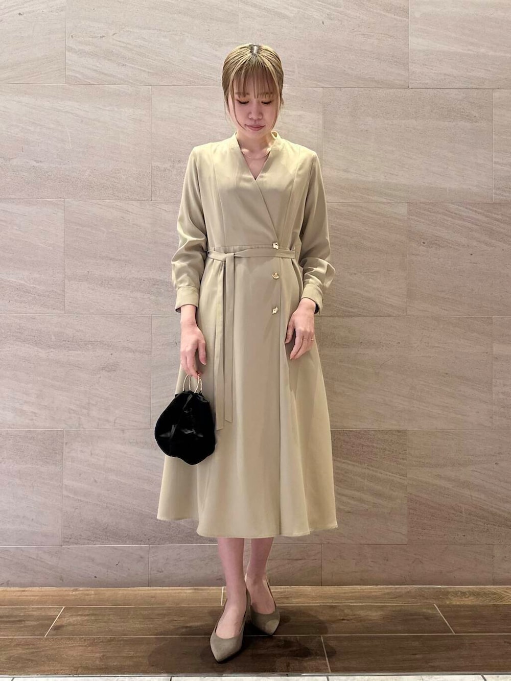 ブラウン系のパンプス、ブラック系のハンドバッグ、ベージュ系のワンピースを着用したレディースの冬コーディネートの2枚目の写真