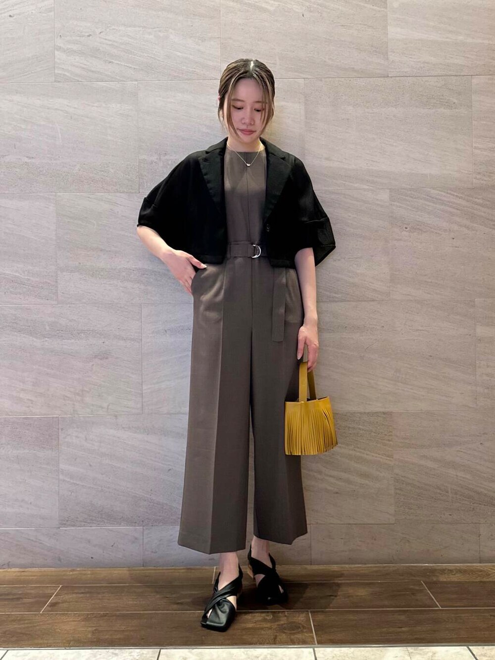 イエロー系のハンドバッグ、ブラック系のその他アウター、ブラウン系のサロペット/オーバーオールを着用したレディースの春コーディネートの3枚目の写真