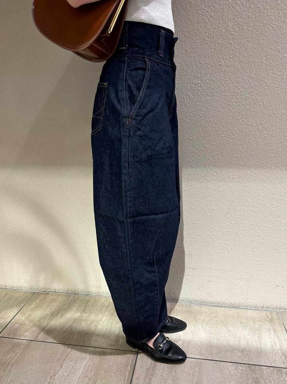 ブラック系のローファー、ホワイト系のニット/セーター、ブルー系のデニムパンツを着用したレディースの秋コーディネートの8枚目の写真