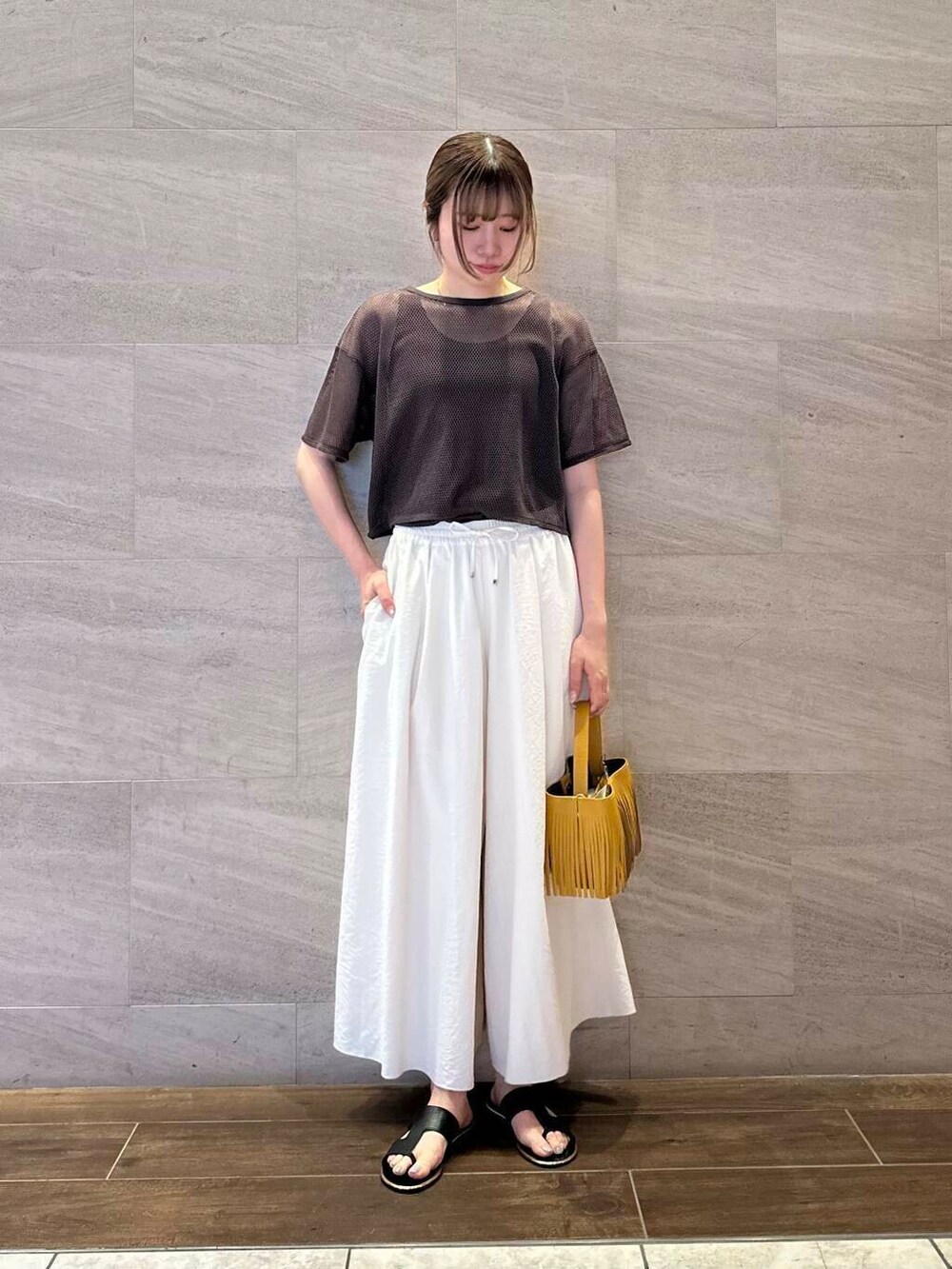 イエロー系のハンドバッグ、ホワイト系のその他パンツ、ブラウン系のTシャツ/カットソーを着用したレディースの夏コーディネートの3枚目の写真