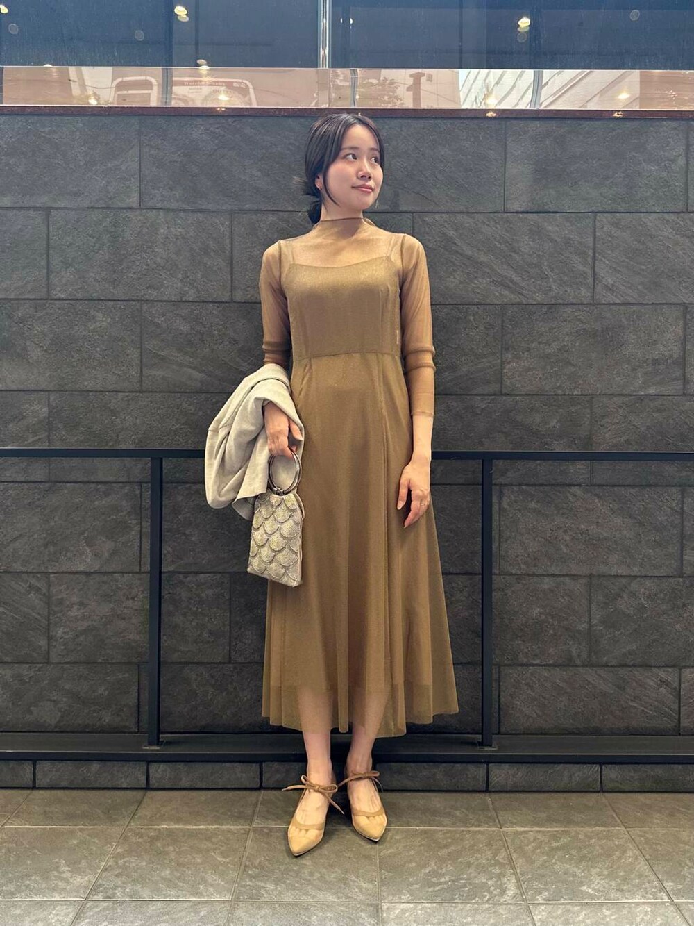 ゴールド系のワンピース、ベージュ系のハンドバッグ、ベージュ系のその他アウターを着用したレディースの夏コーディネートの2枚目の写真