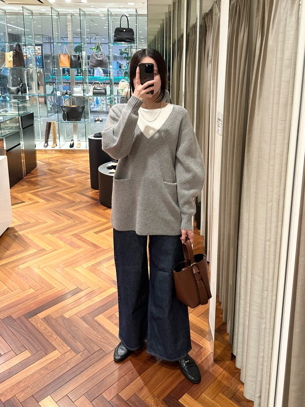 グレー系のニット/セーター、ホワイト系のTシャツ/カットソー、ブルー系のデニムパンツを着用したレディースの秋コーディネートの2枚目の写真