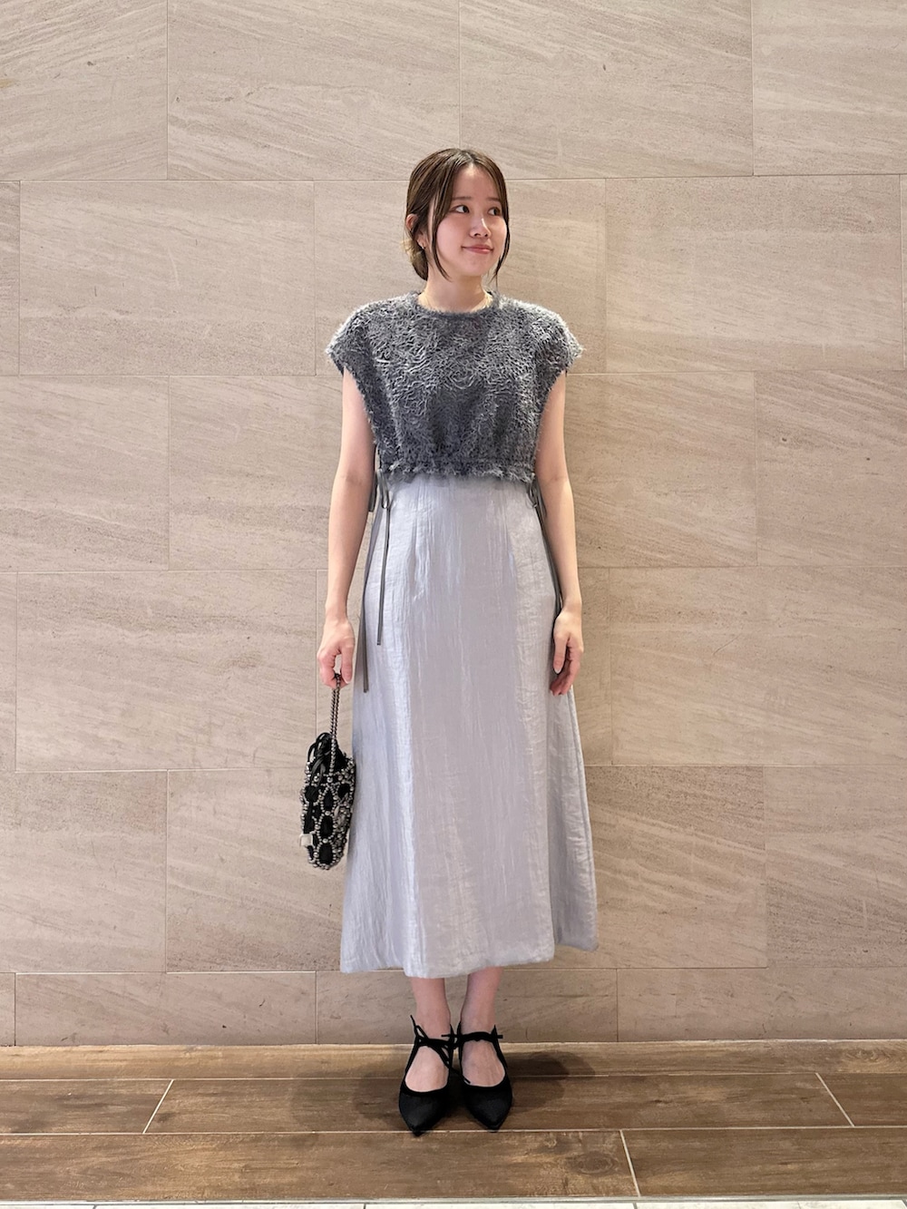 ブルー系のワンピース、ブラック系のハンドバッグ、ブラック系のパンプスを着用したレディースの夏コーディネートの2枚目の写真