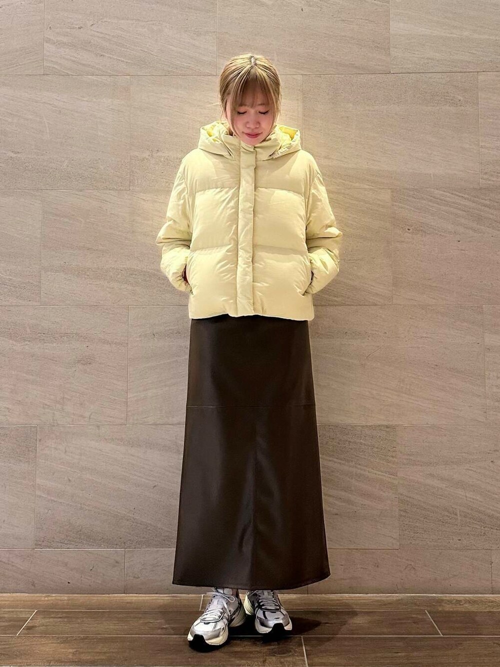 ブラウン系のスカート、イエロー系のダウンジャケット/コート、ホワイト系のスニーカーを着用したレディースの冬コーディネートの3枚目の写真