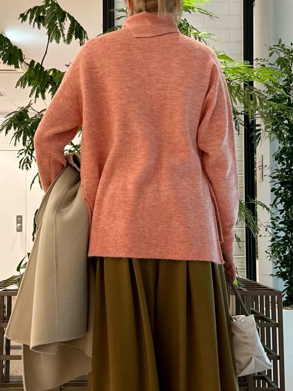 ベージュ系のステンカラーコート、ベージュ系のその他パンツ、ピンク系のニット/セーターを着用したレディースの冬コーディネートの6枚目の写真