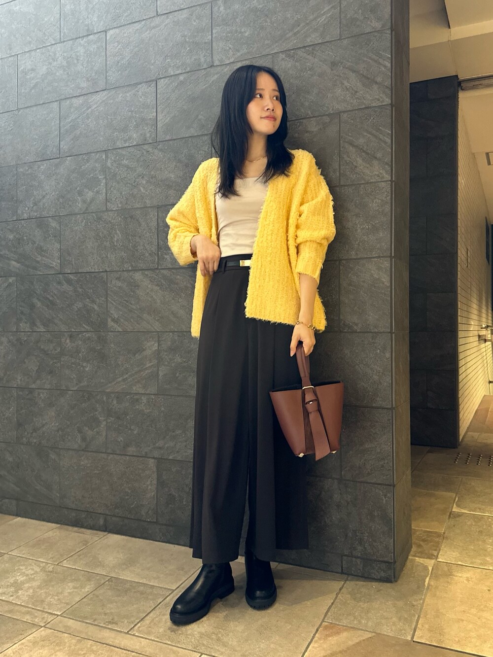 イエロー系のカーディガン/ボレロ、グレー系のその他パンツ、ベージュ系のキャミソールを着用したレディースの秋コーディネートの2枚目の写真