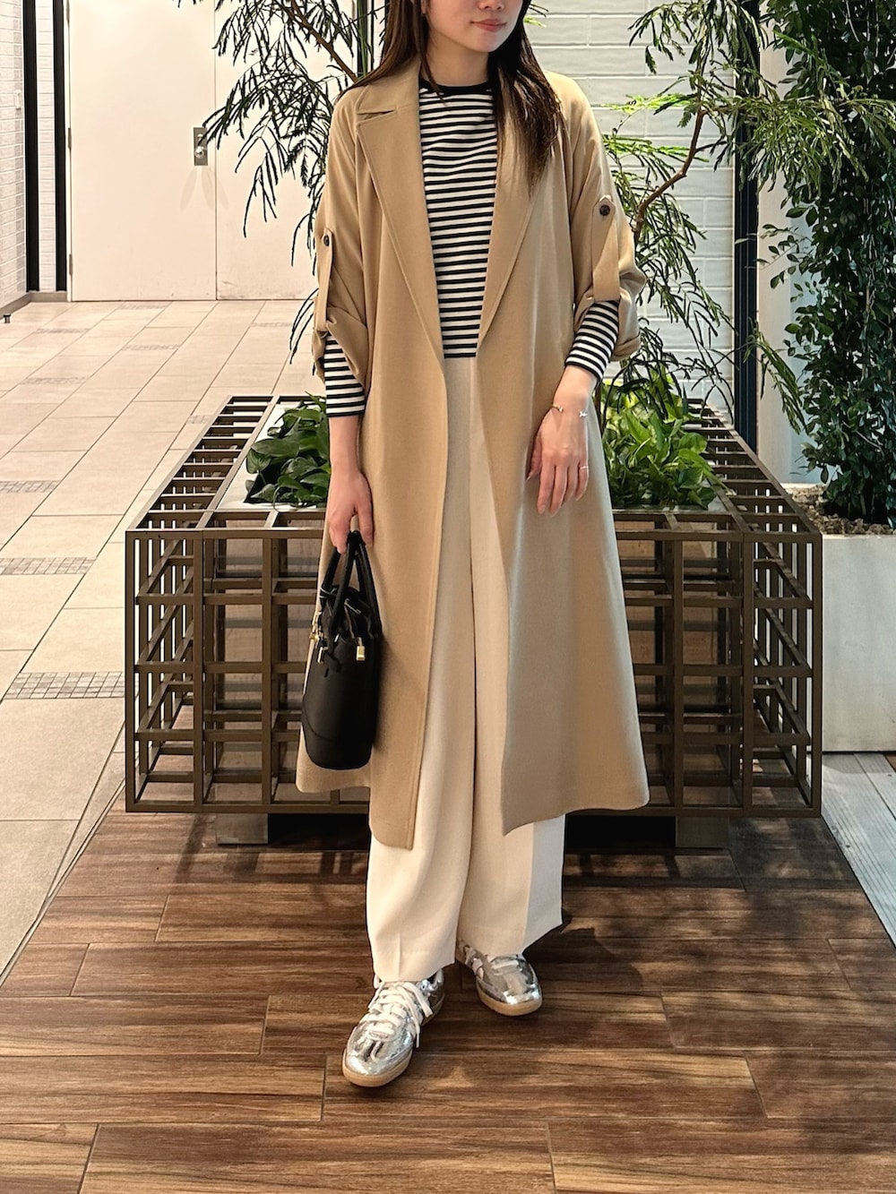 ベージュ系のトレンチコート、ホワイト系のTシャツ/カットソー、ブラック系のショルダーバッグを着用したレディースの春コーディネートの3枚目の写真