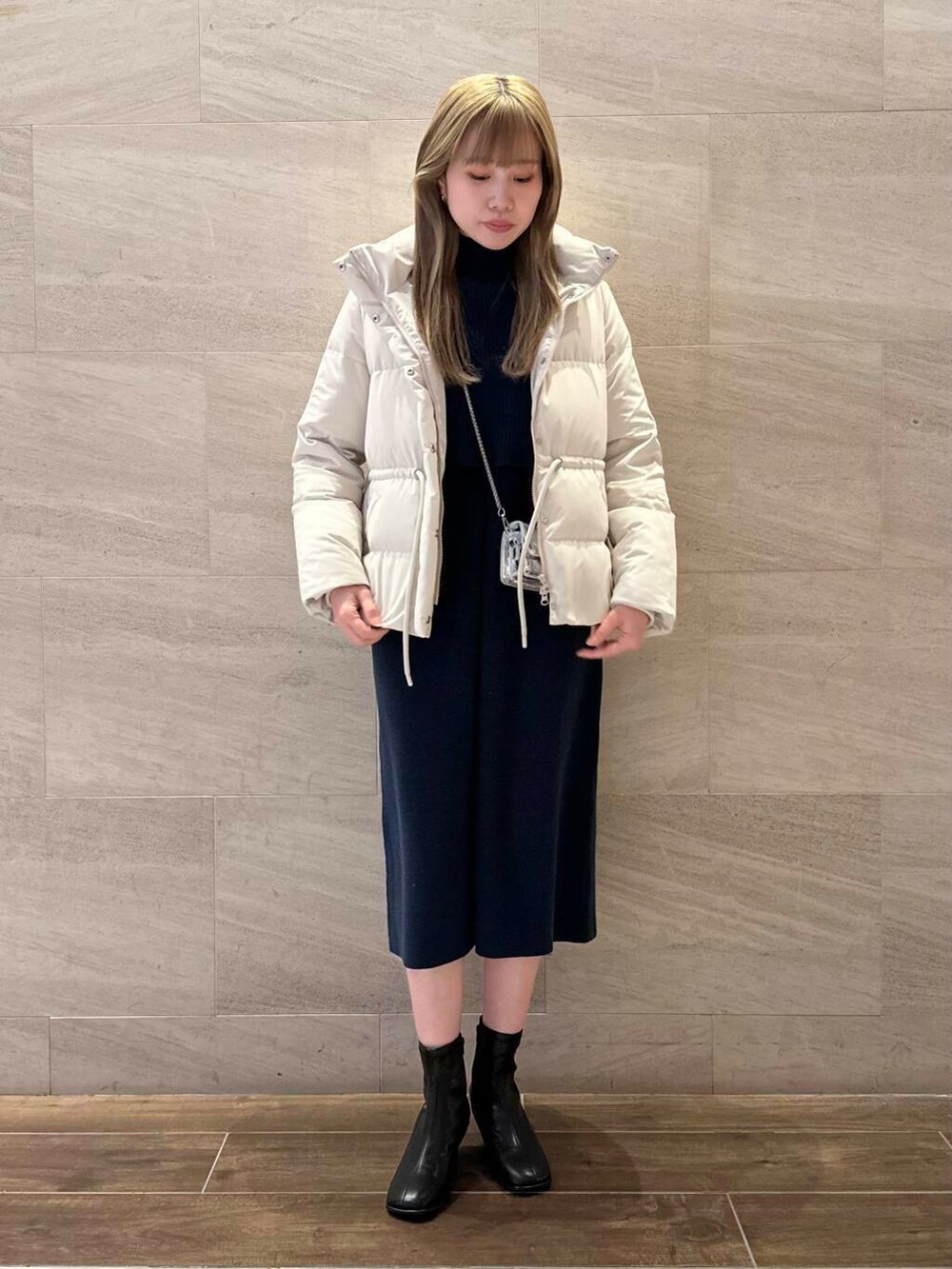 ブラック系のブーツ、ホワイト系のダウンジャケット/コート、ブルー系のワンピースを着用したレディースの冬コーディネートの2枚目の写真