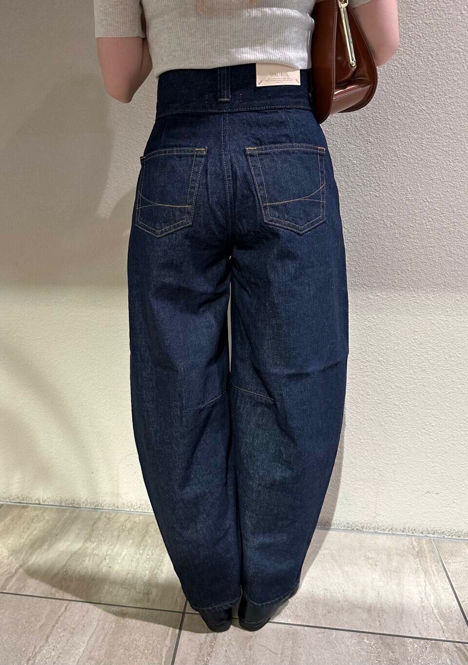 ブラック系のローファー、ホワイト系のニット/セーター、ブルー系のデニムパンツを着用したレディースの秋コーディネートの9枚目の写真