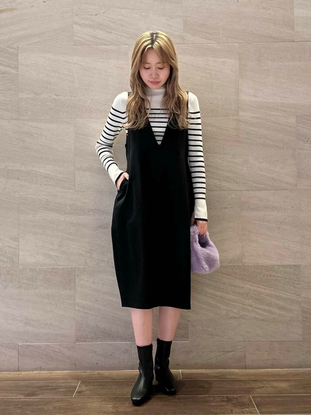 ホワイト系のニット/セーター、ブラック系のジャンパースカート、ブラック系のブーツを着用したレディースの冬コーディネートの4枚目の写真