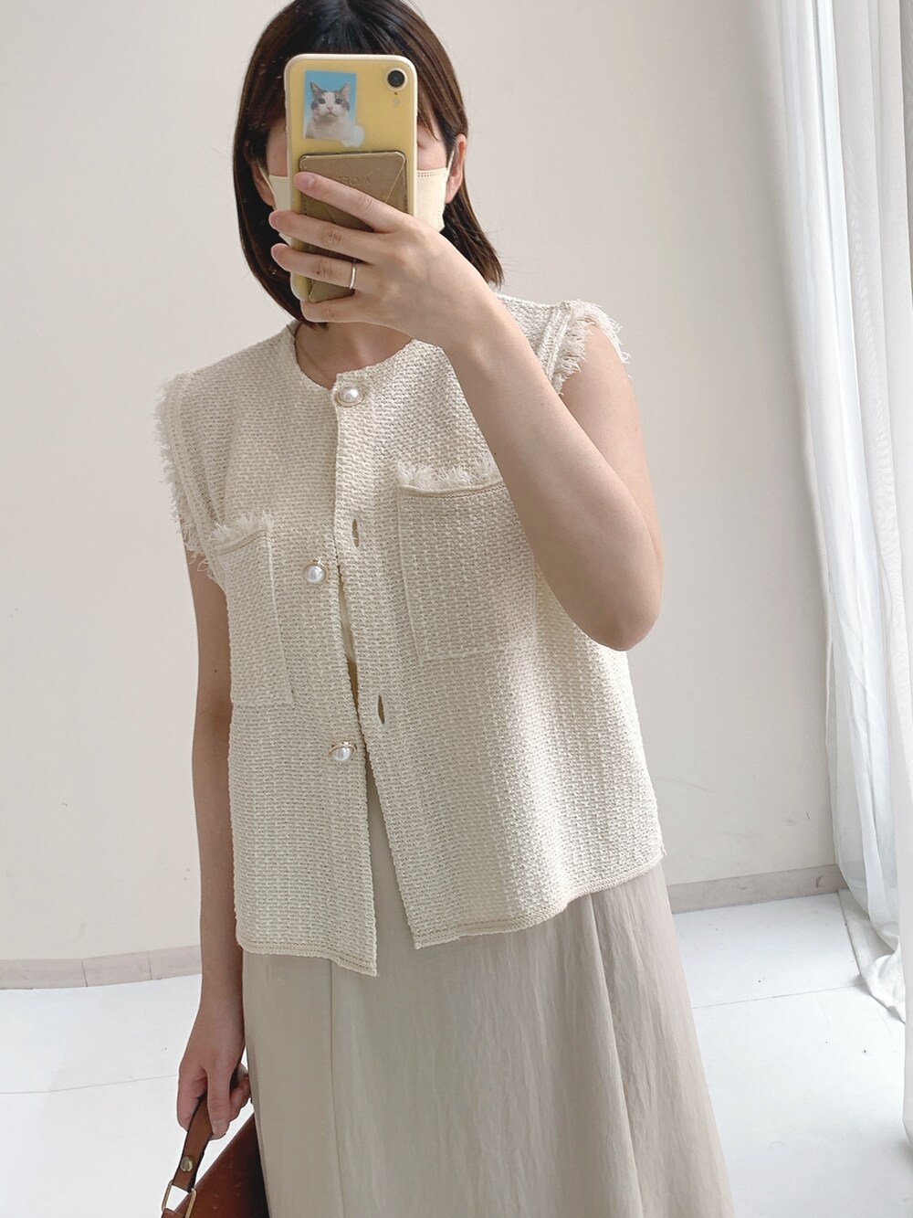 ホワイト系のベスト、ベージュ系のスカートを着用したレディースの夏コーディネートの3枚目の写真