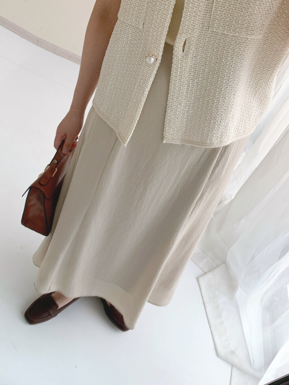 ホワイト系のベスト、ベージュ系のスカートを着用したレディースの夏コーディネートの4枚目の写真
