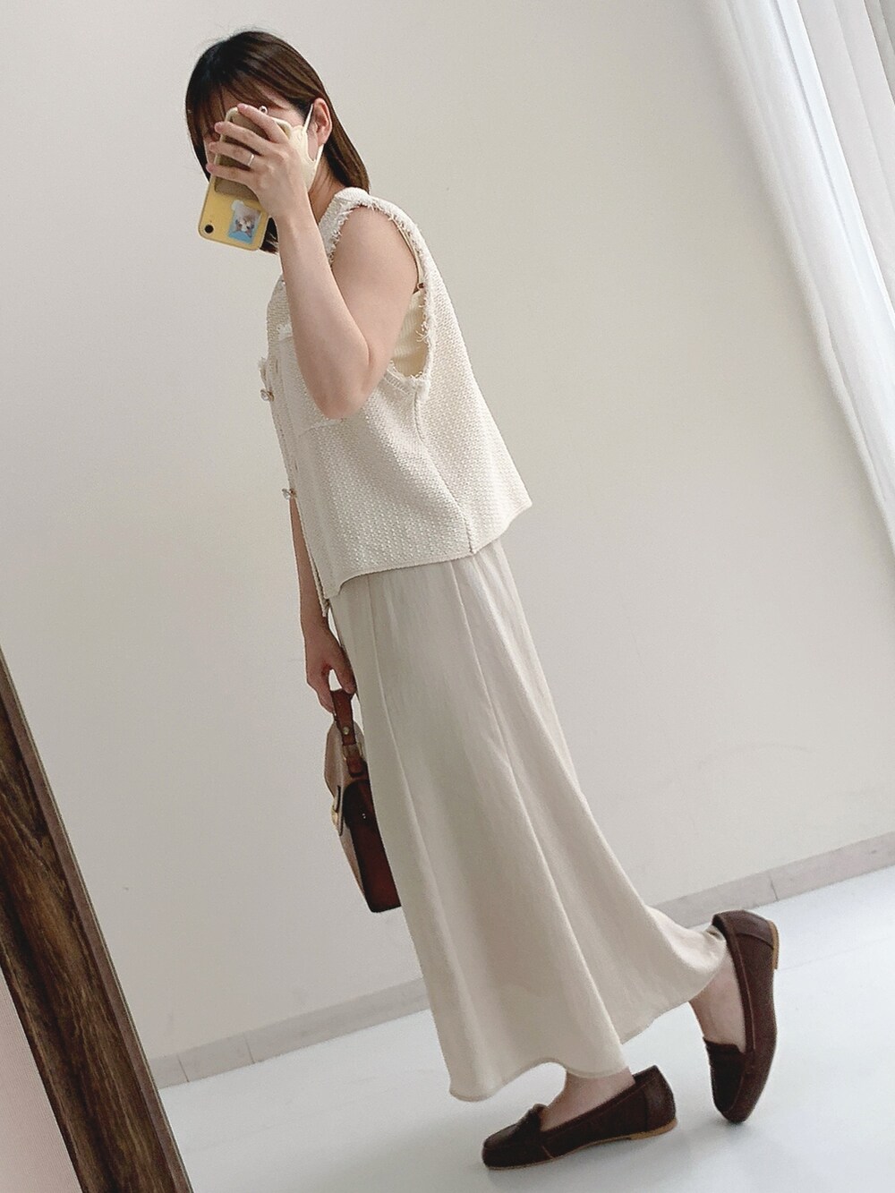 ホワイト系のベスト、ベージュ系のスカートを着用したレディースの夏コーディネートの2枚目の写真