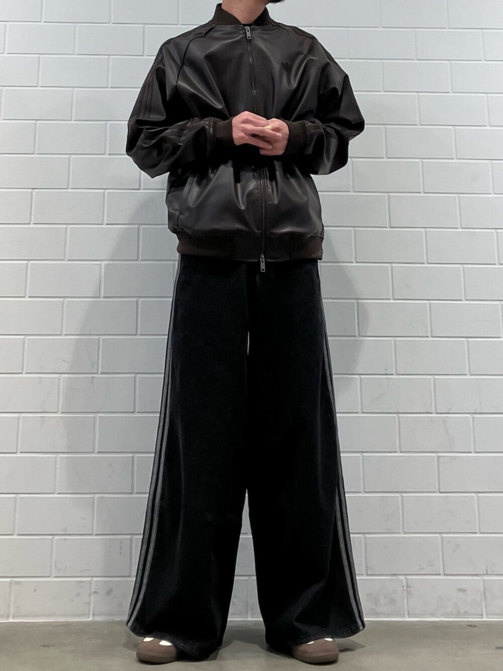 ホワイト系のスニーカー、ブラウン系のジャージ、ブラック系のデニムパンツを着用したメンズの冬コーディネートの2枚目の写真