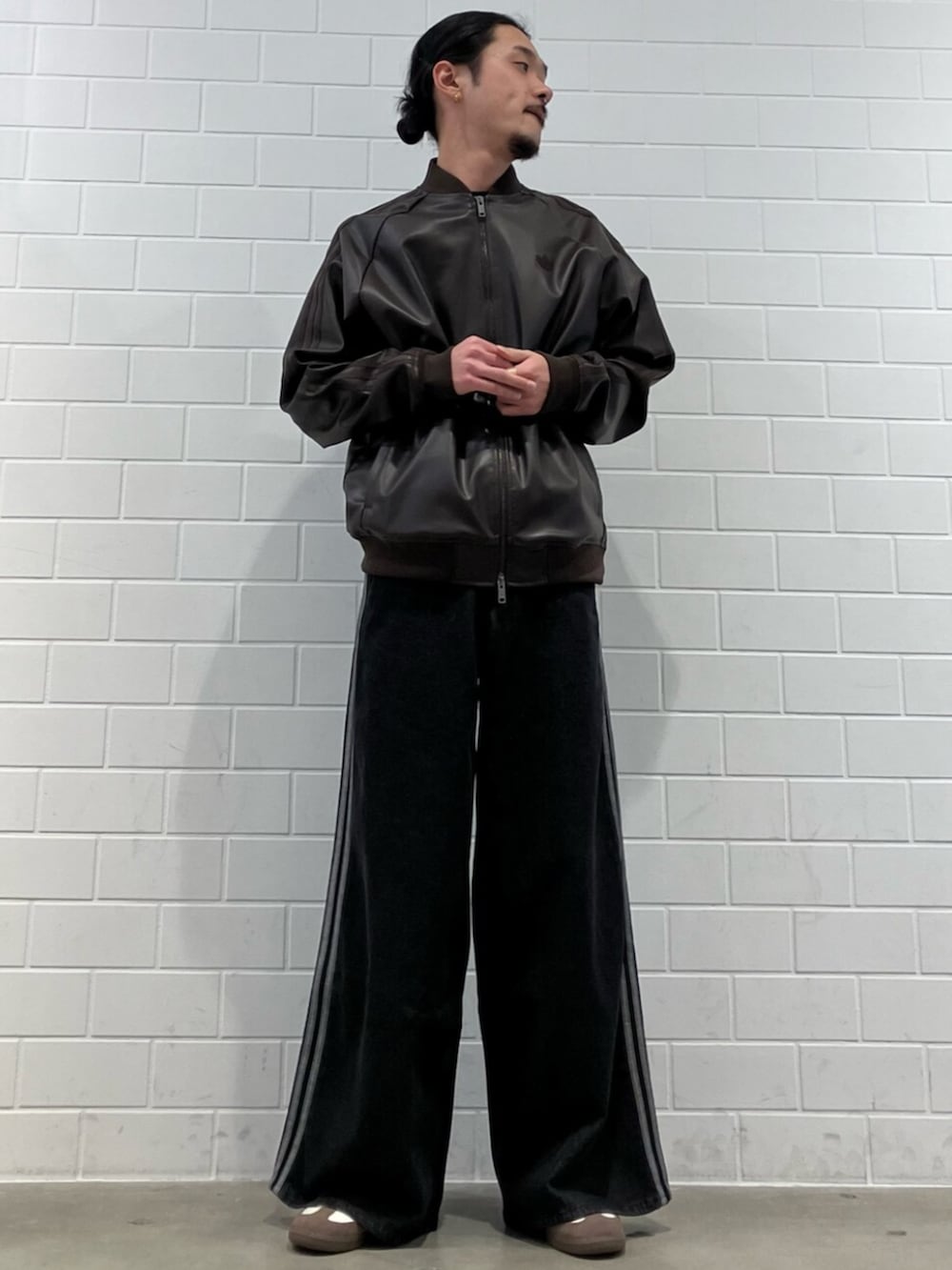 ホワイト系のスニーカー、ブラウン系のジャージ、ブラック系のデニムパンツを着用したメンズの冬コーディネートの3枚目の写真