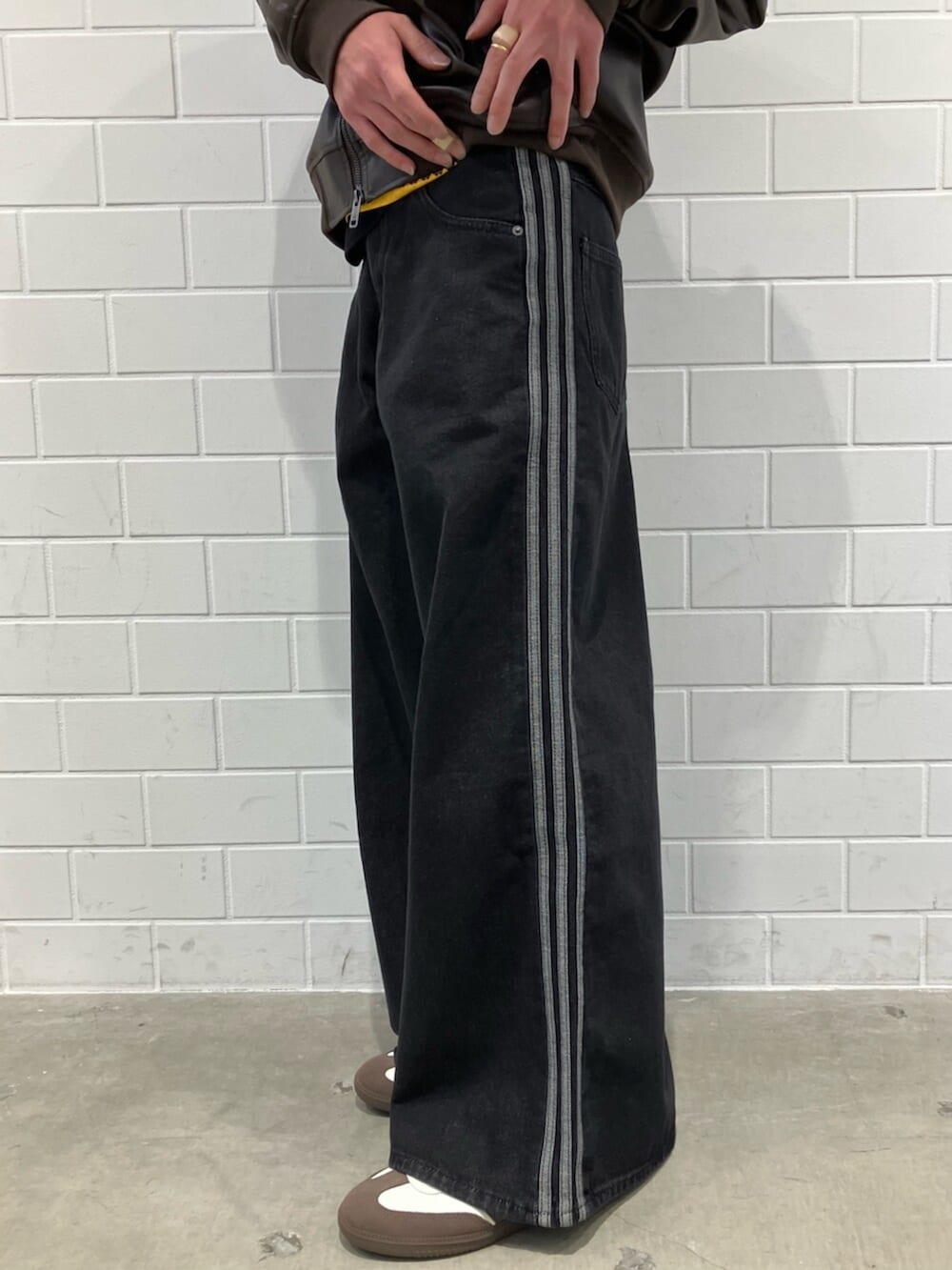 ホワイト系のスニーカー、ブラウン系のジャージ、ブラック系のデニムパンツを着用したメンズの冬コーディネートの5枚目の写真