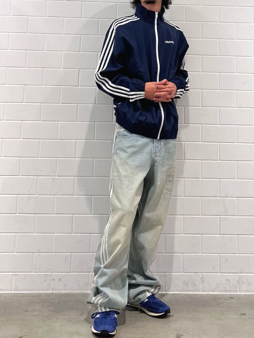 ブルー系のナイロンジャケット、ブルー系のデニムパンツ、ブルー系のシューズを着用したメンズの秋コーディネートの2枚目の写真