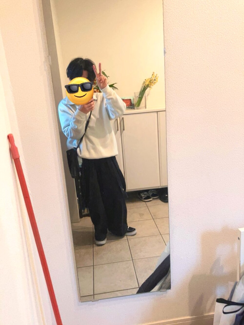 グレー系のデニムパンツ、ベージュ系のニット/セーター、ブラック系のショルダーバッグを着用したメンズの冬コーディネートの2枚目の写真