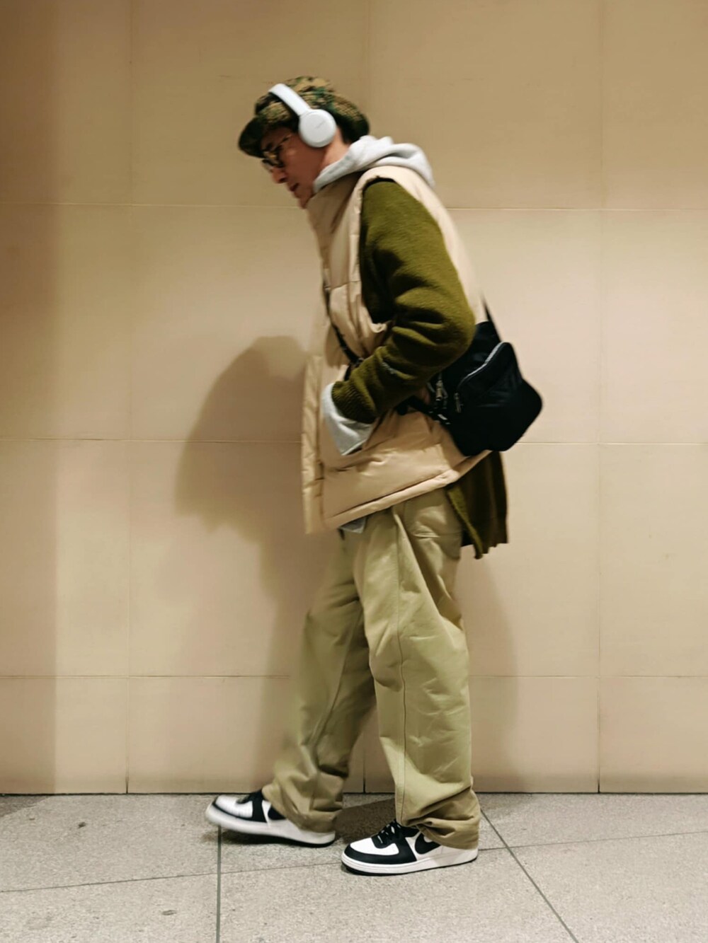 ベージュ系のダウンベスト、グリーン系のニット/セーター、ベージュ系のチノパンツを着用したメンズの冬コーディネートの2枚目の写真