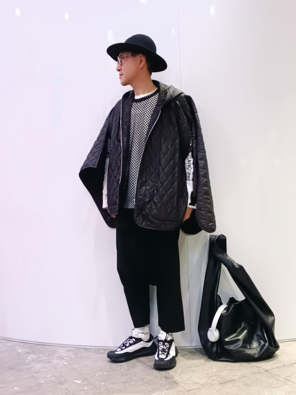 ホワイト系のスニーカー、ブラック系のポンチョ、ホワイト系のTシャツ/カットソーを着用したメンズの春コーディネートの2枚目の写真