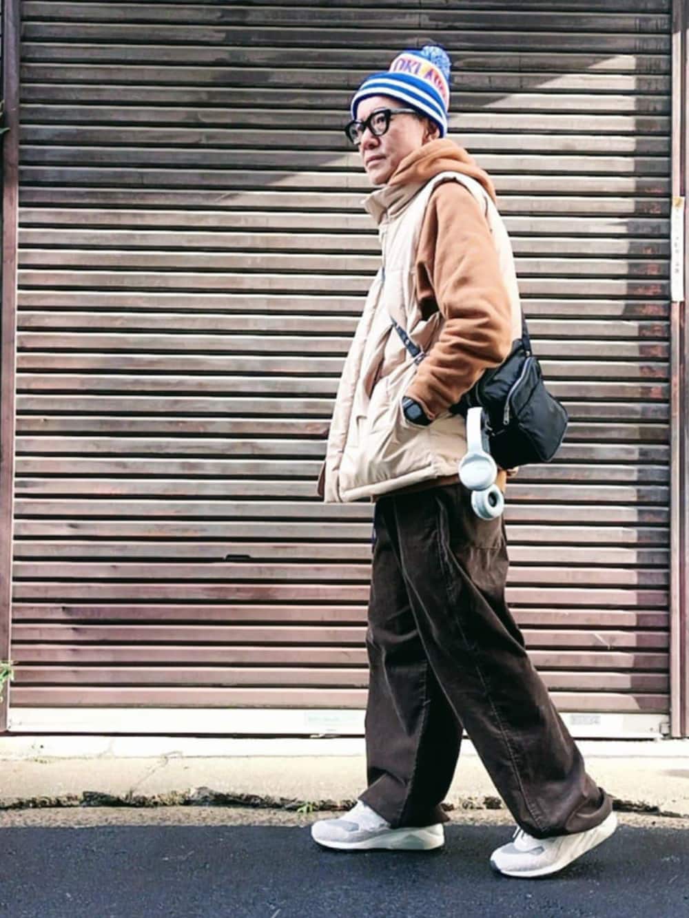 ブラウン系のパーカー、ベージュ系のダウンベスト、ブラウン系のパンツを着用したメンズの冬コーディネートの2枚目の写真